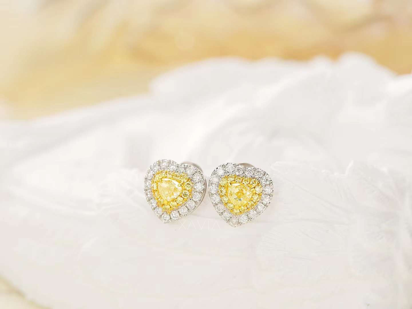 Yellow heart diamond earrings with dual halo placed on white feathers